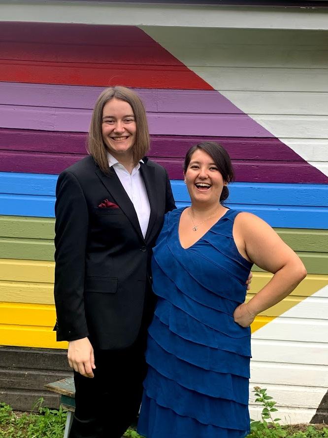 Aimee Oda'16 and Melissa Korniejczuk'17 pose in front of a rainbow wall.