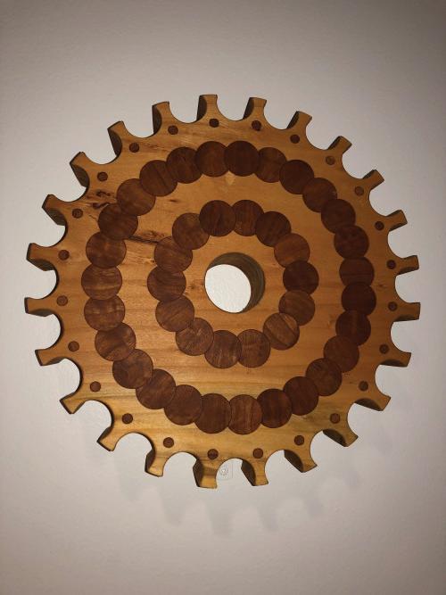 A wooden gear made of interlocking circular pieces of wood of various colors.